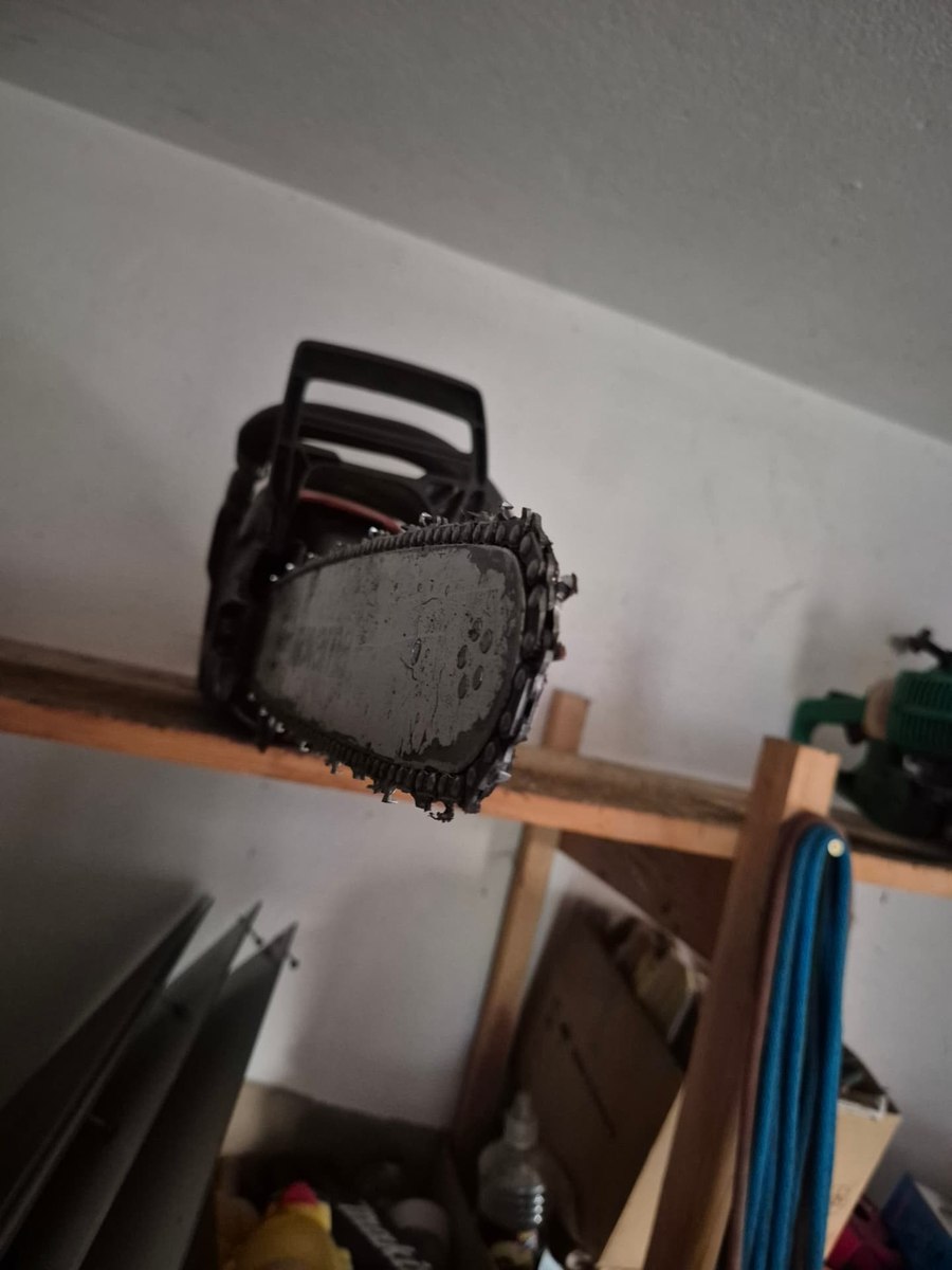 Motorsäge mit Kettenschwert auf einem Holzregal in der Werkstatt